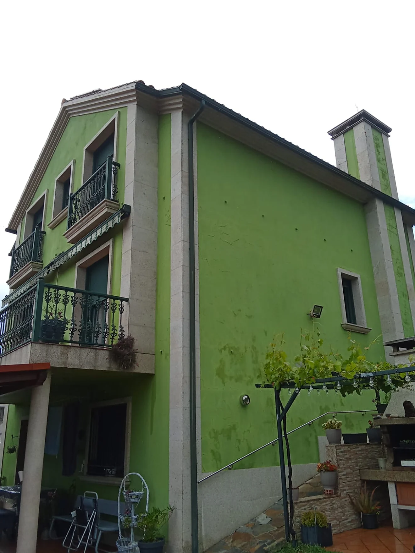 La misma fachada antes de la intervención, con la pintura verde deslucida y manchas de humedad