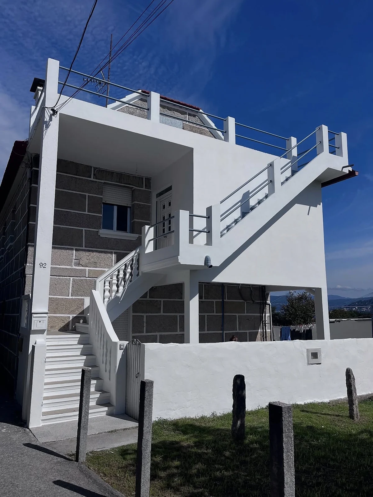 Vivienda de bloque de granito con fachada, escalera y muro pintados en blanco